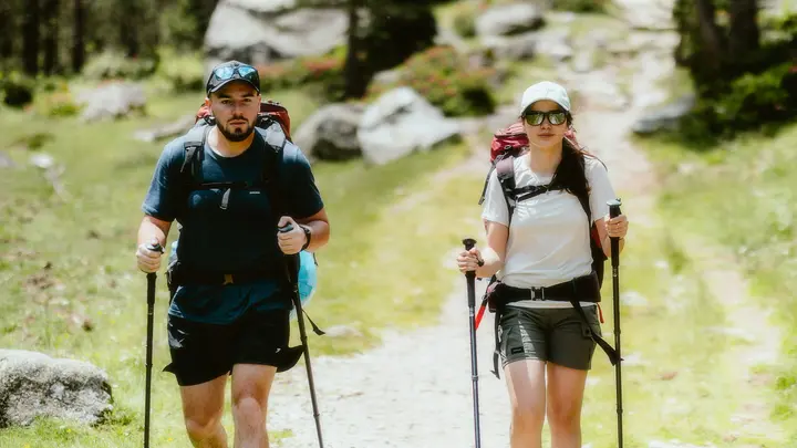 Ein Mann und eine Frau mit Rucksäcken und Stöcken wandern auf einem Bergpfad